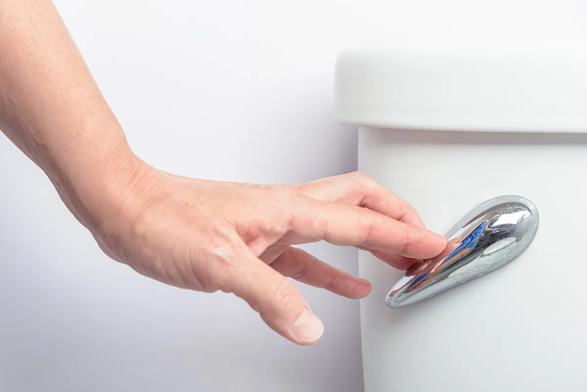 Slow flushing toilet being flushed by hand before professional toilet repair
