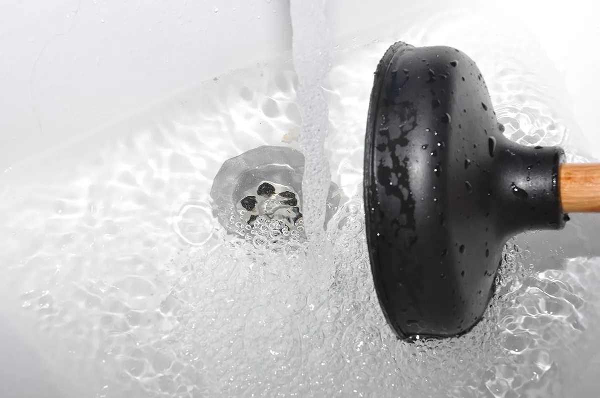 Bathtub drain clogged with standing water and plunger