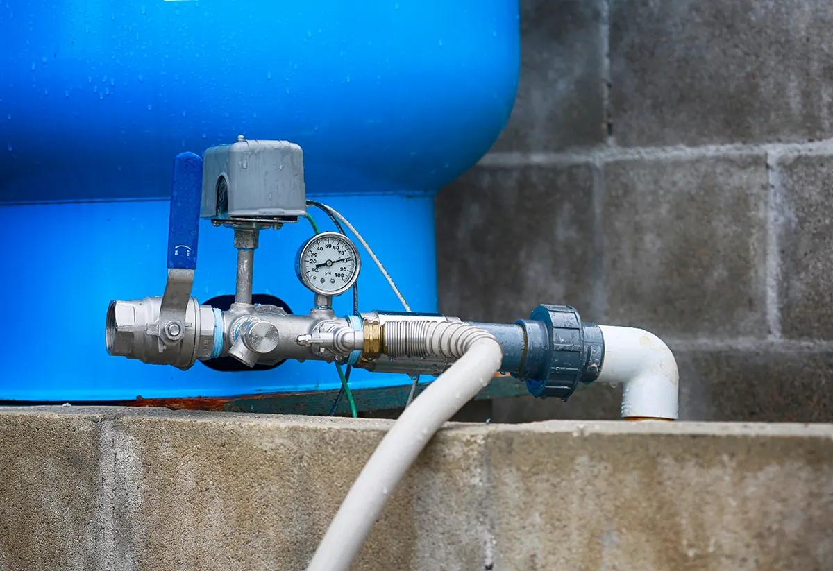 Water well tank with pressure gauge and plumbing connections
