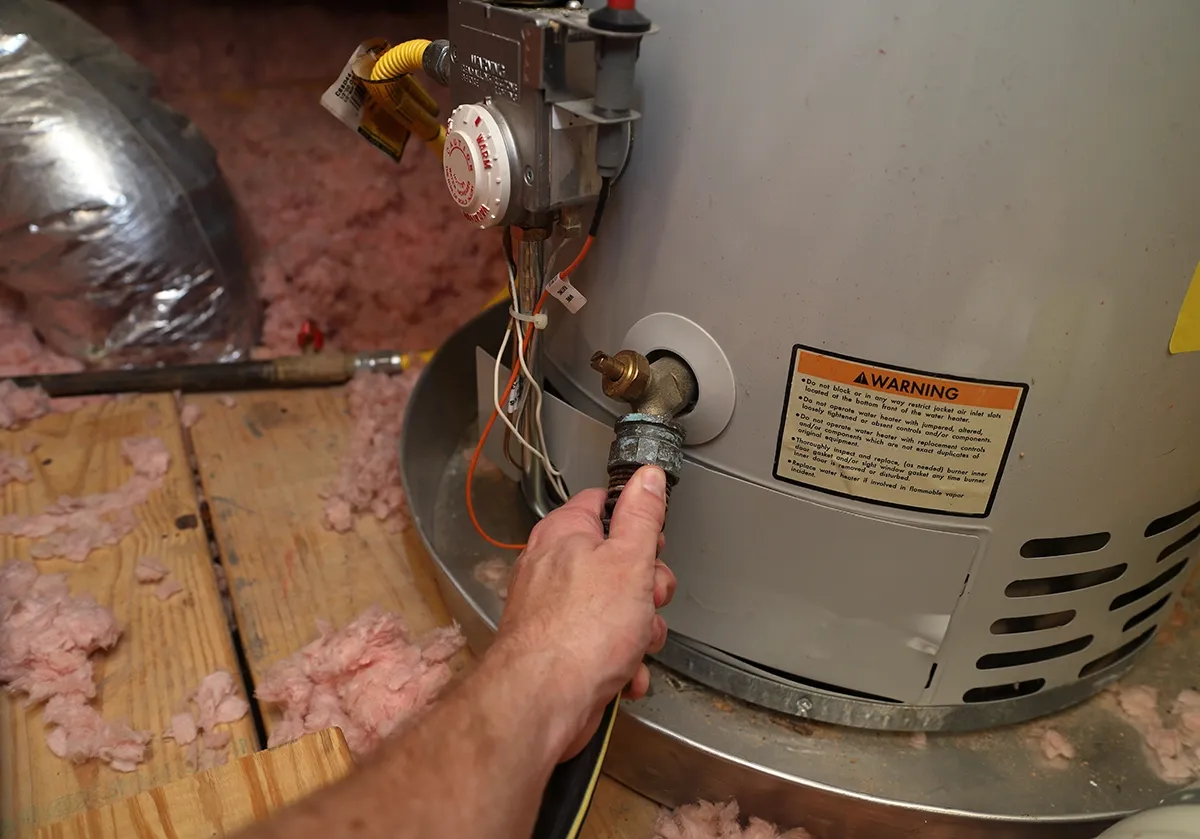 Water heater Bessemer City repair with a technician checking a valve on a tank-style water heater.
