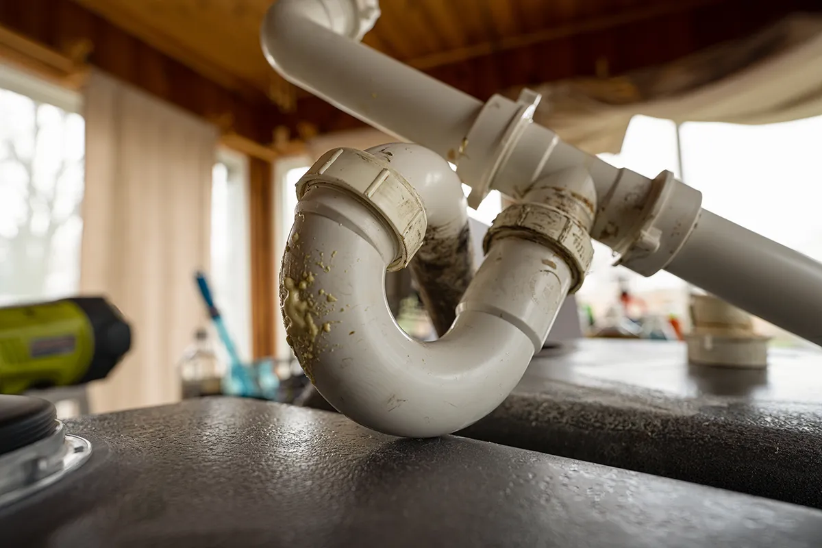 Close-up of a p trap on an exposed plumbing drain line showing the curved pipe that helps block sewer gases.