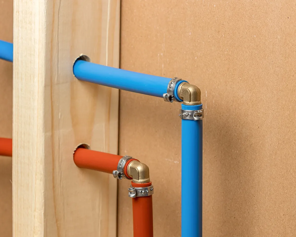 PEX plumbing with red and blue water supply lines installed behind a residential wall.