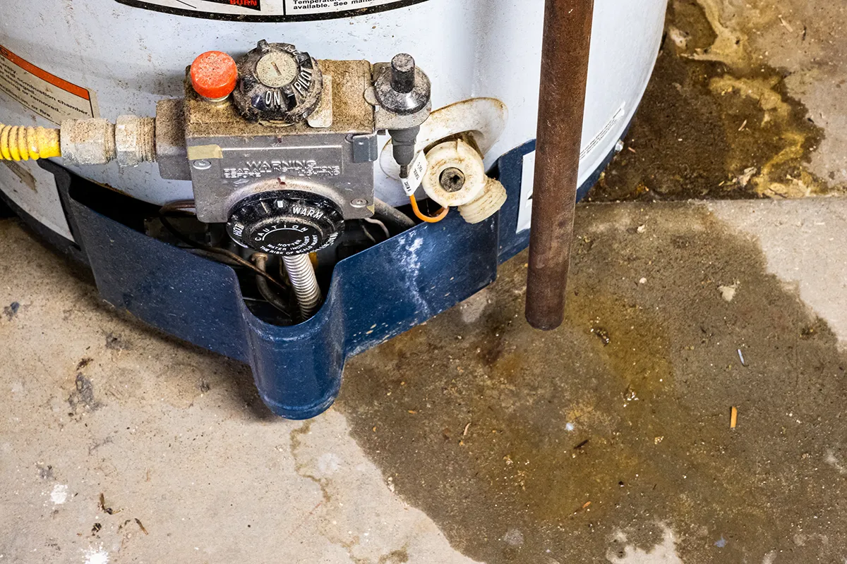 Water heater leaking from the bottom in Monroe with water pooling around the base of the tank.