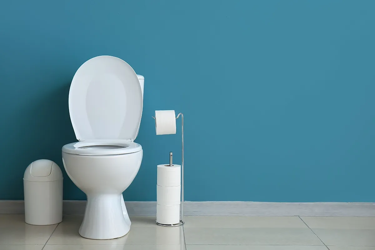 Toilet running continuously in Salisbury with white toilet and bathroom fixtures against a blue wall.