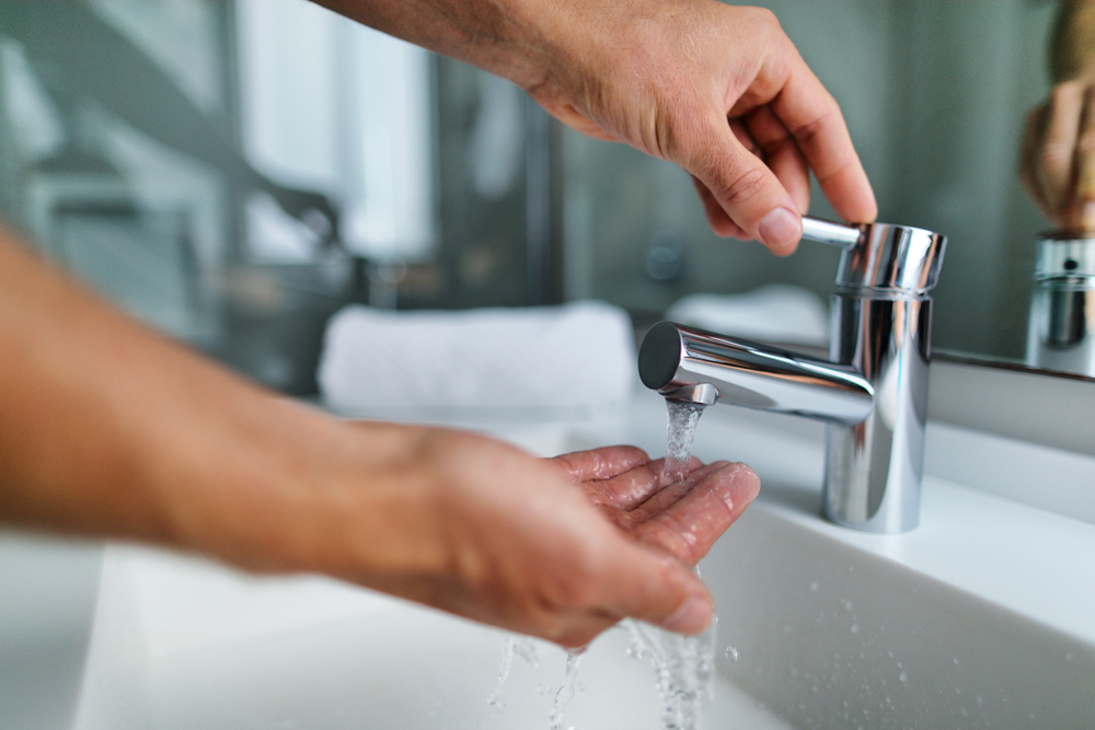 man's hands turning on the bathroom sink and testing the water pressure